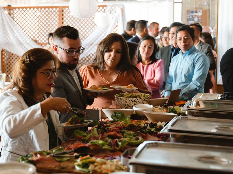Guests serving themselves at a spread of shared dishes